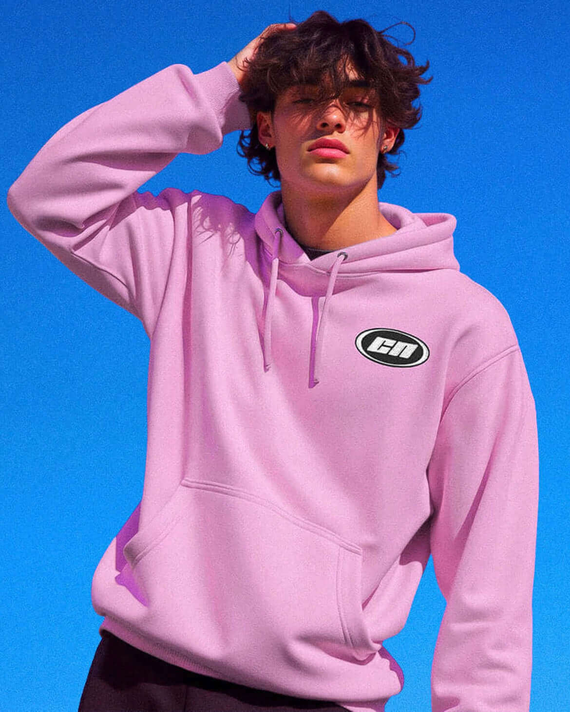 Pastel pink pullover hoodie on model against blue sky, featuring Club Neo logo and adjustable drawstrings.