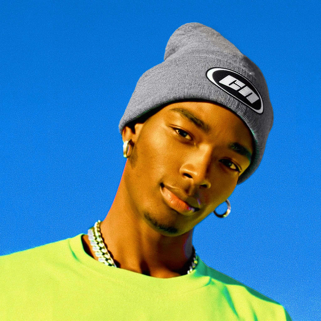 Person wearing a gray beanie with a logo against a blue background