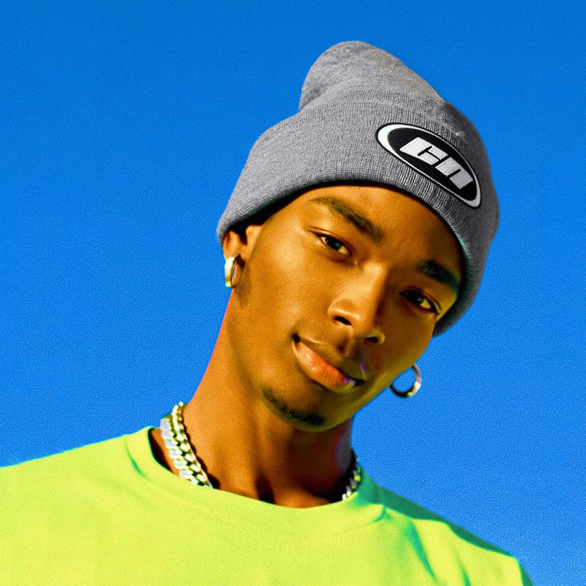 Person wearing a gray beanie with a logo against a blue background