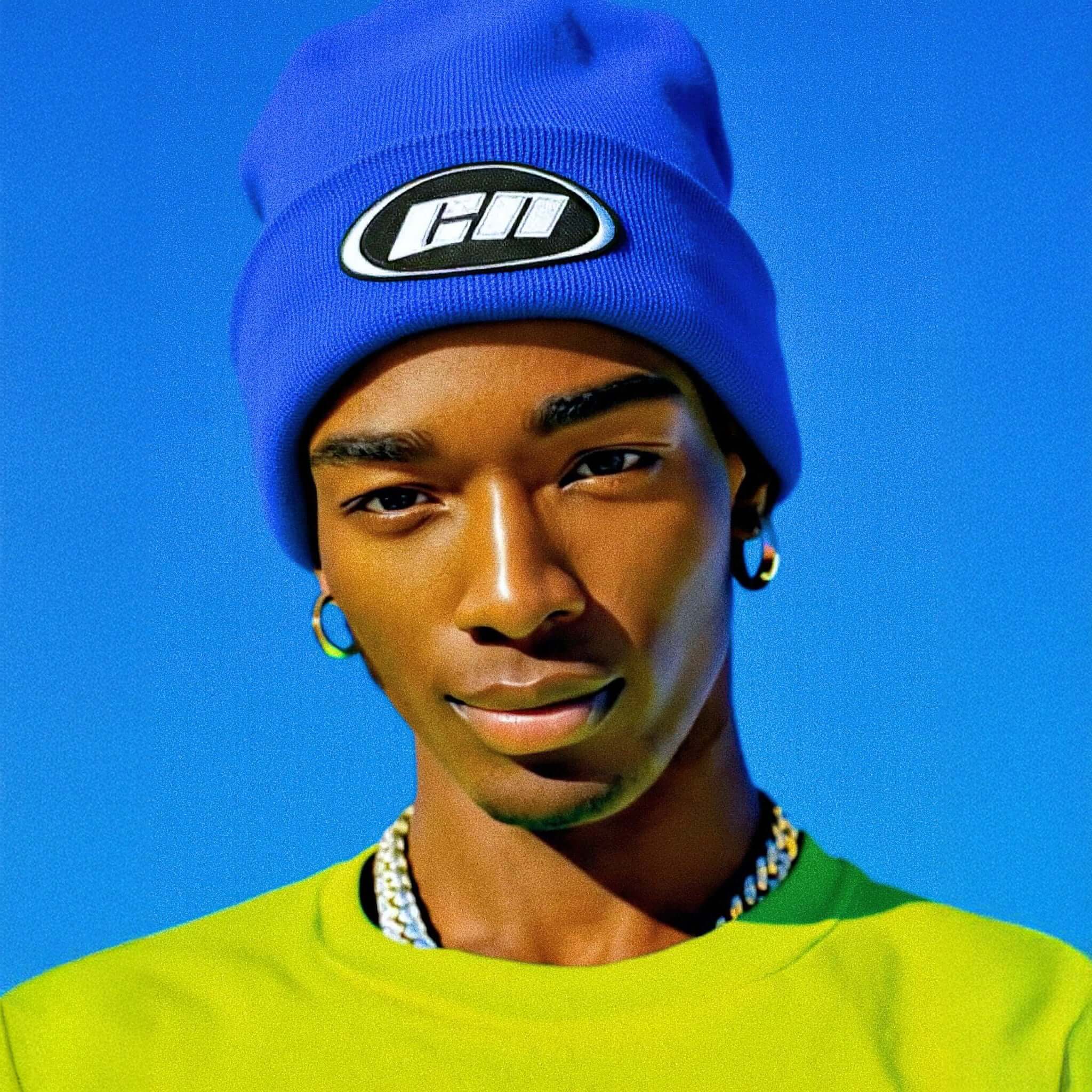 Person wearing a blue beanie with a logo against a clear blue sky