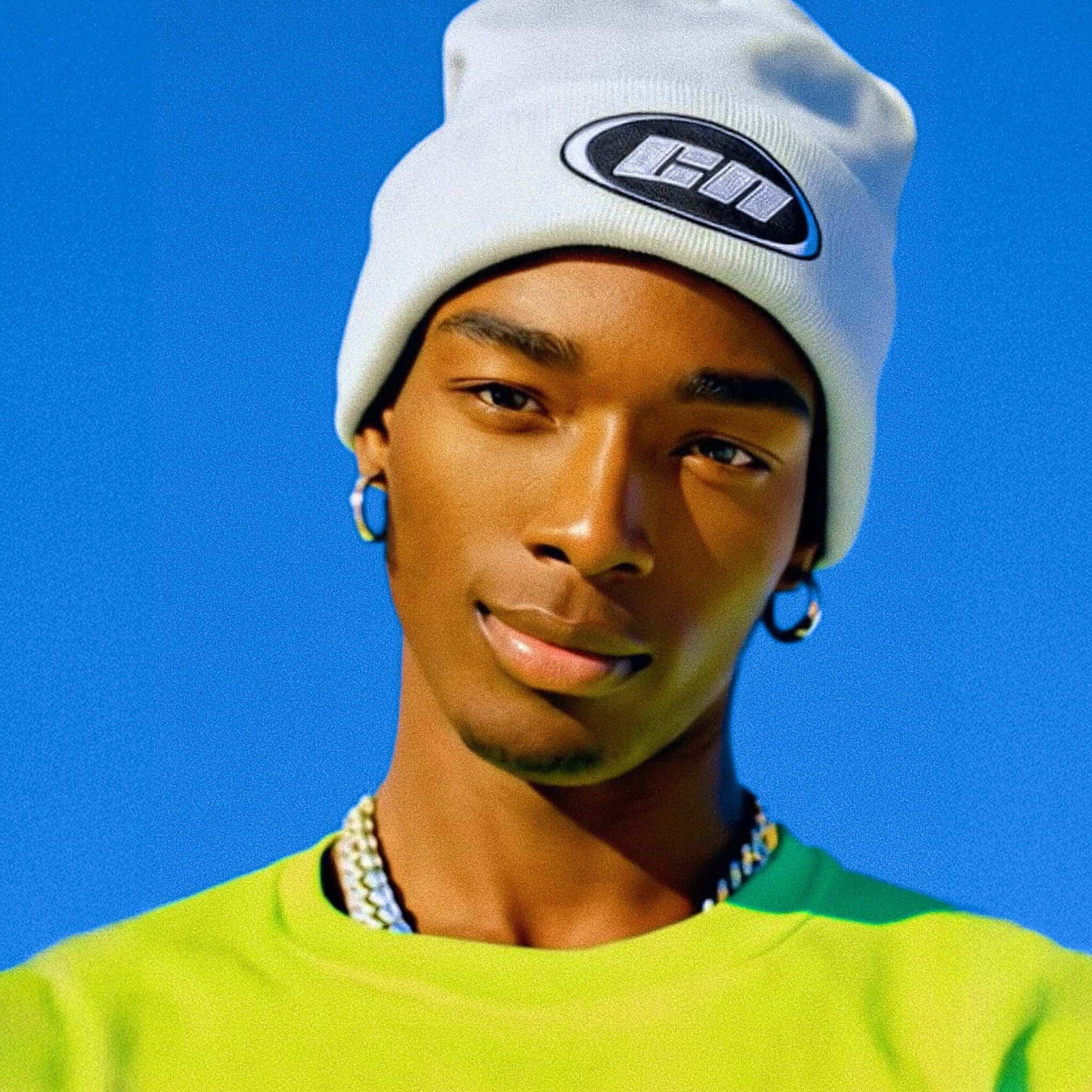 Person wearing a white beanie with a logo against a blue sky