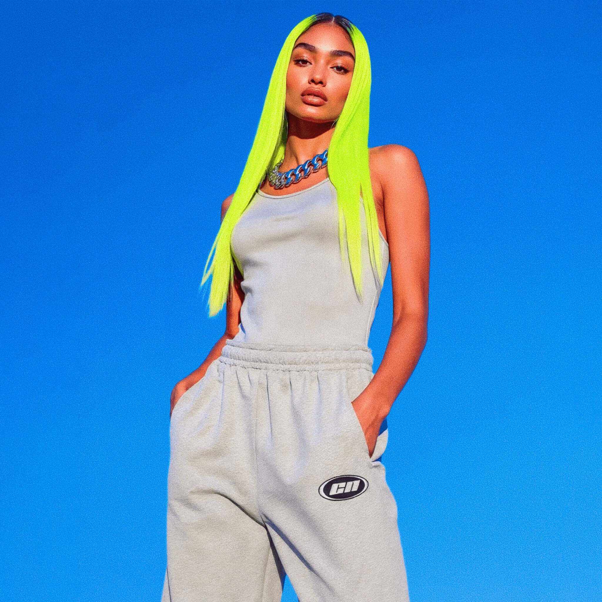 Person wearing a light gray tracksuit with a blue background