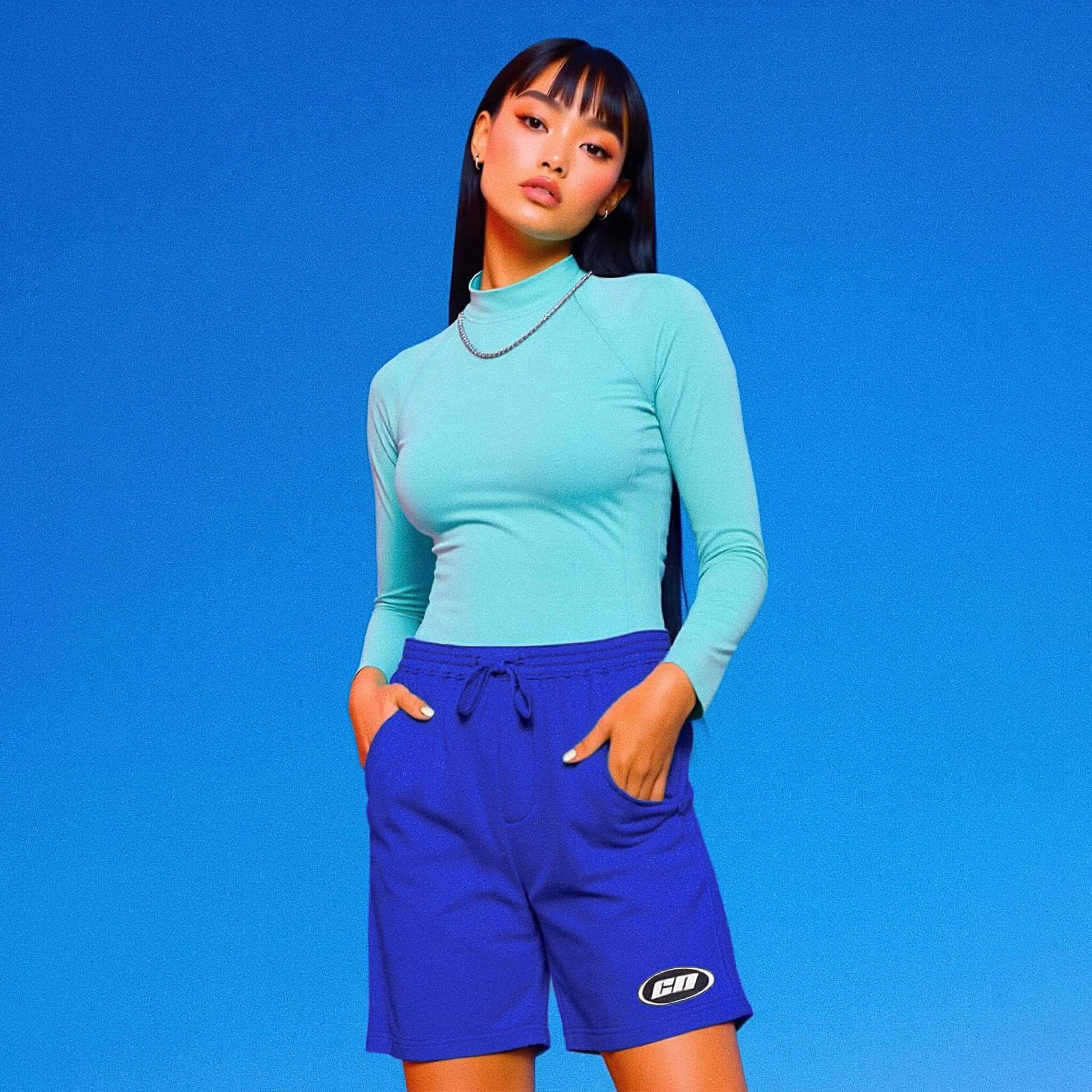 Person wearing a turquoise long-sleeve top and blue shorts against a blue background