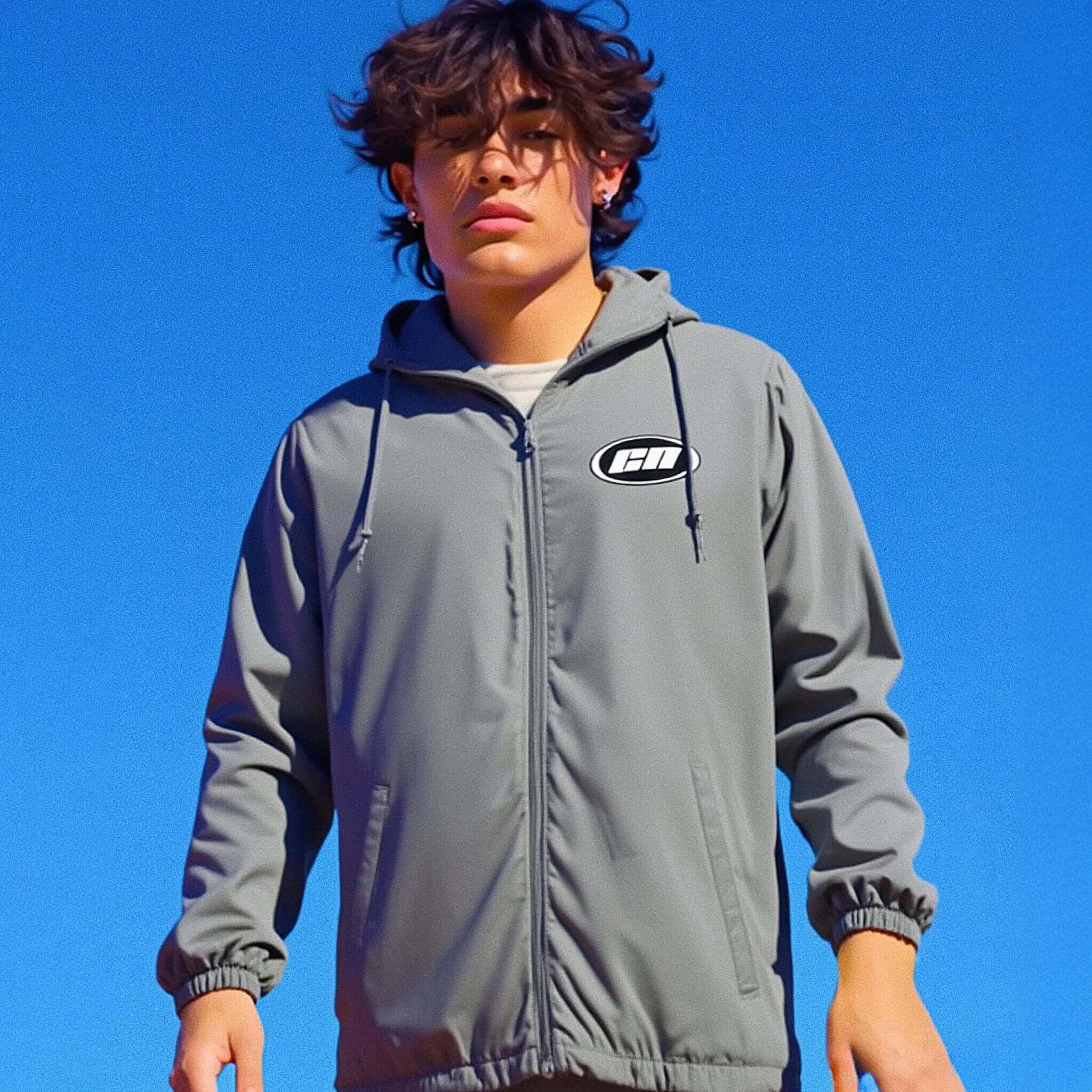 Person wearing a gray hoodie with a logo against a clear blue sky
