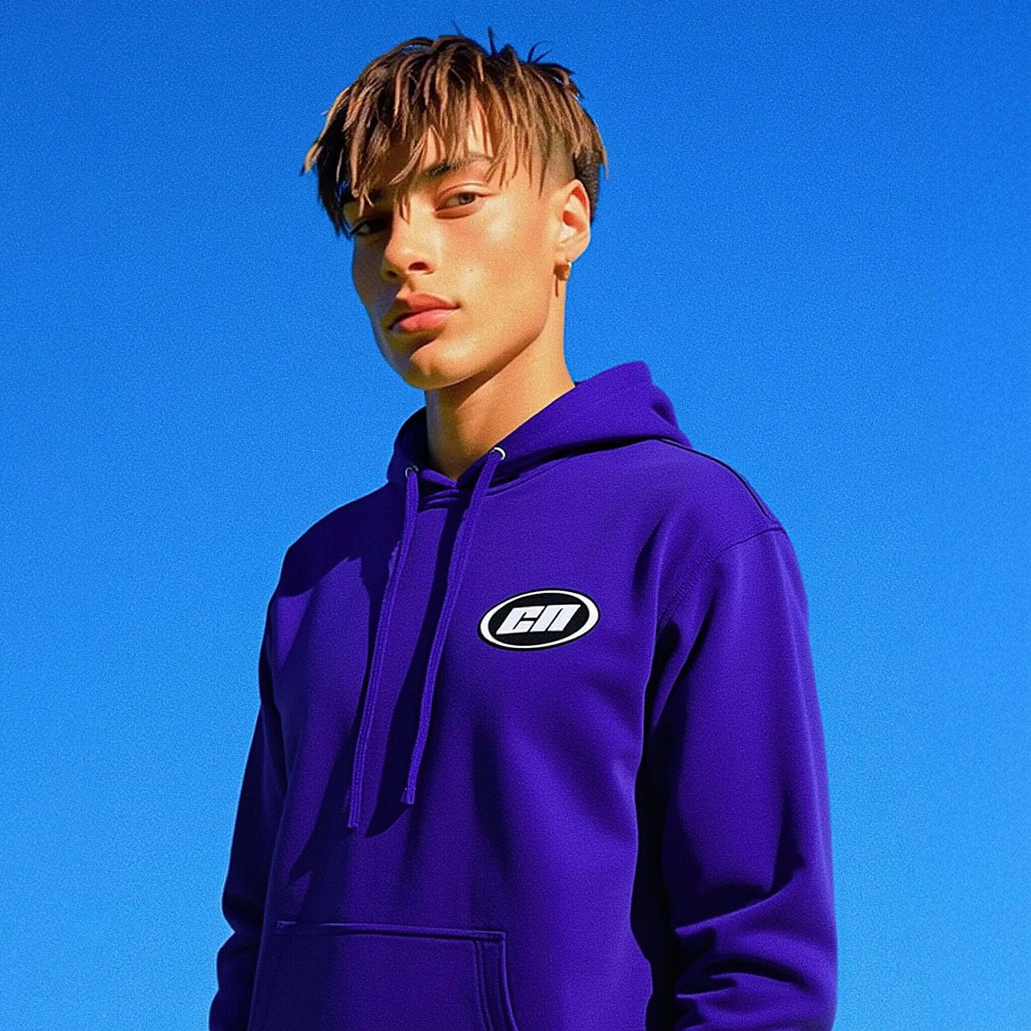 Person wearing a purple hoodie with a logo against a clear blue sky