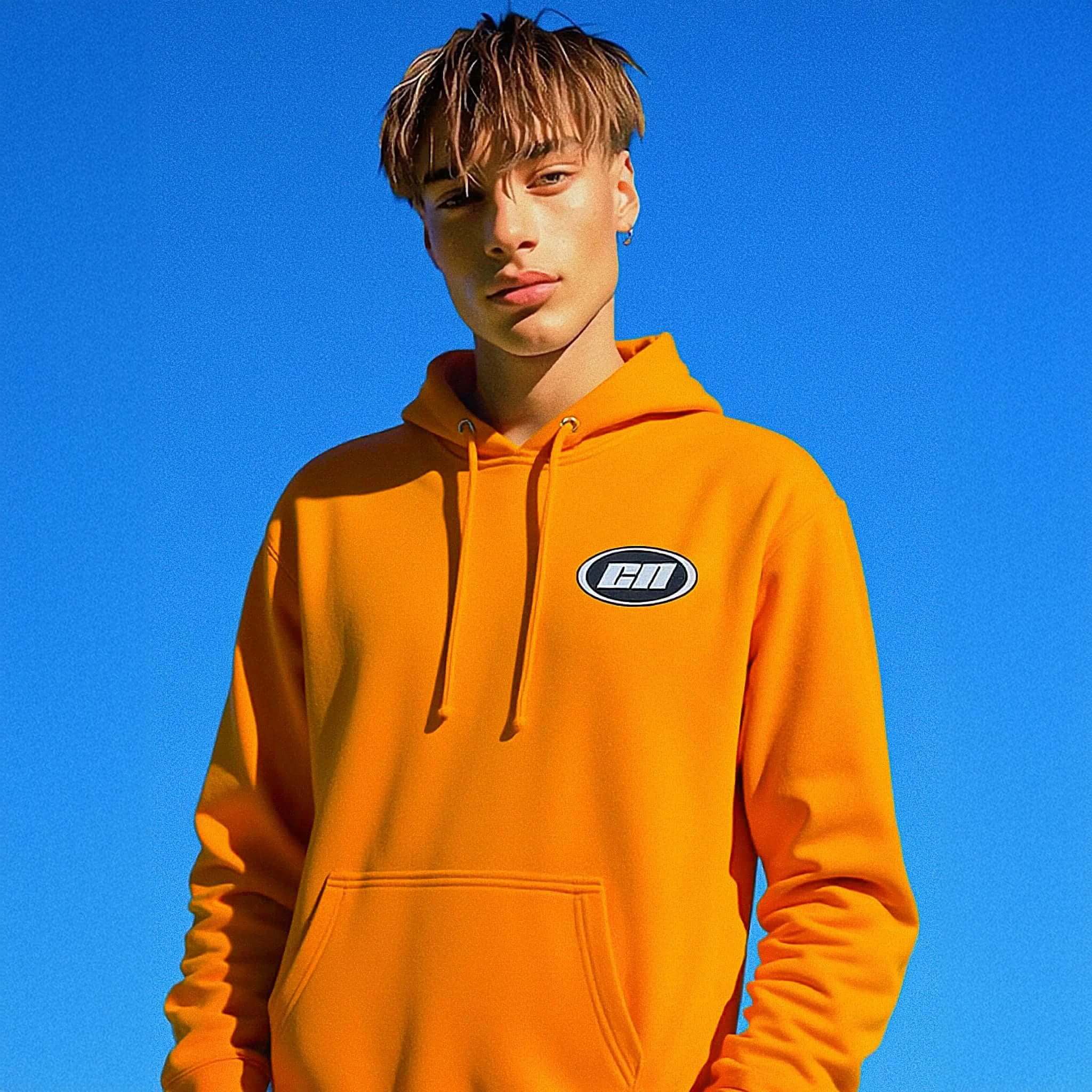 Person wearing an orange hoodie with a logo against a blue sky