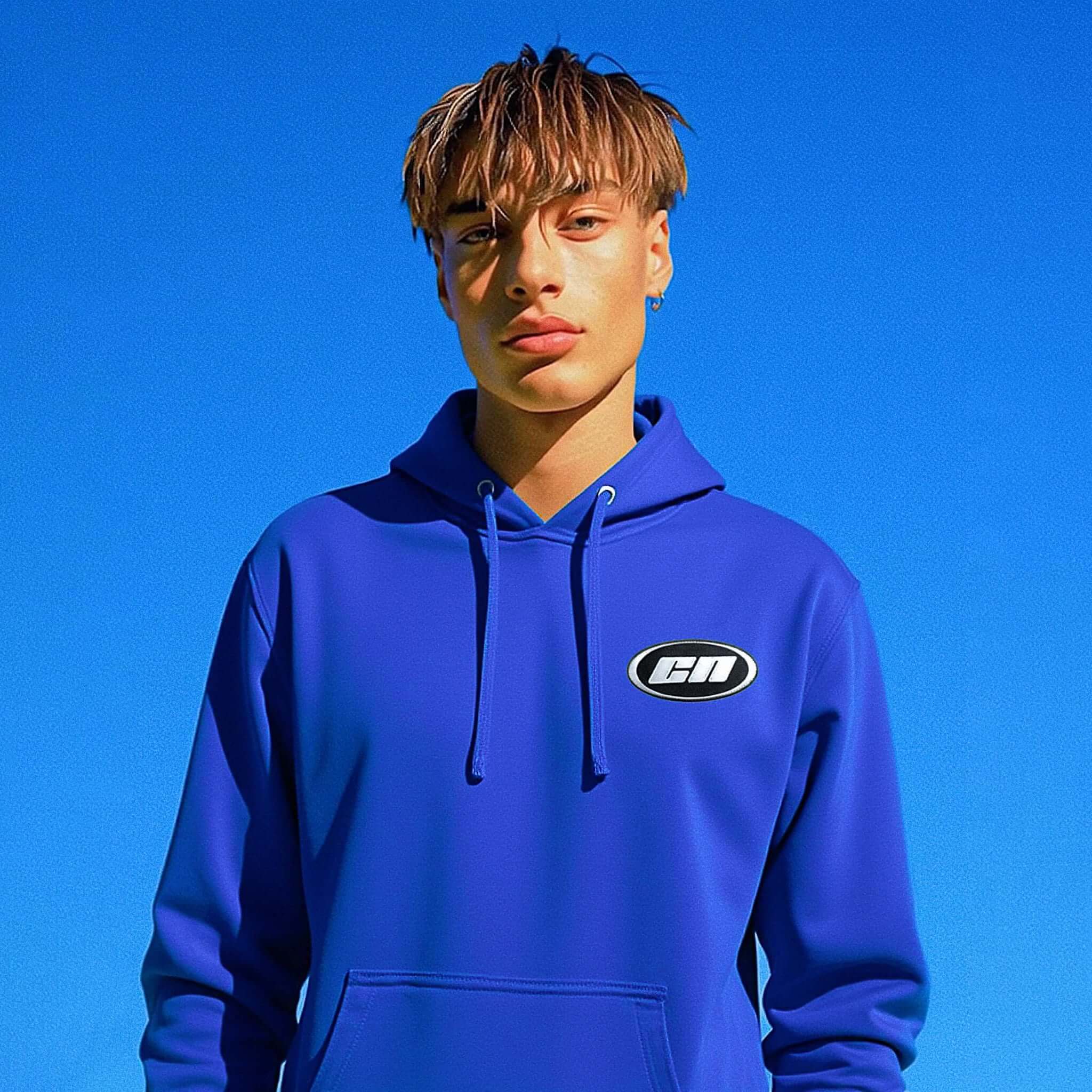 Person wearing a blue hoodie with a logo against a clear blue sky